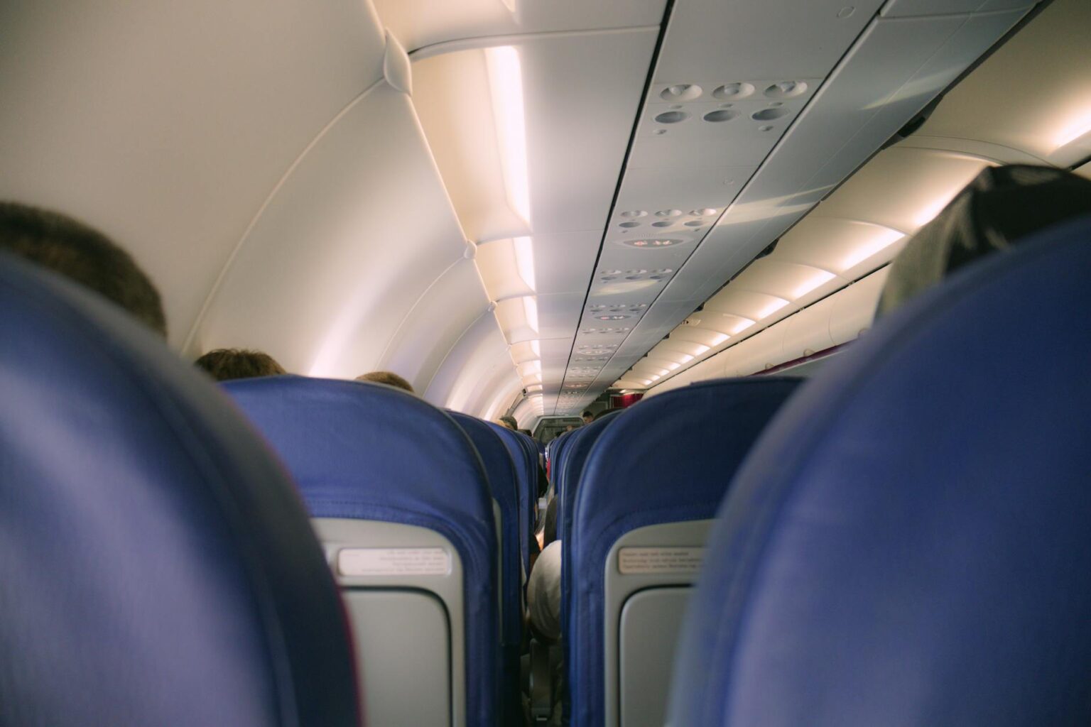 Modern airplane cabin interior with rows of passenger seats and overhead compartments