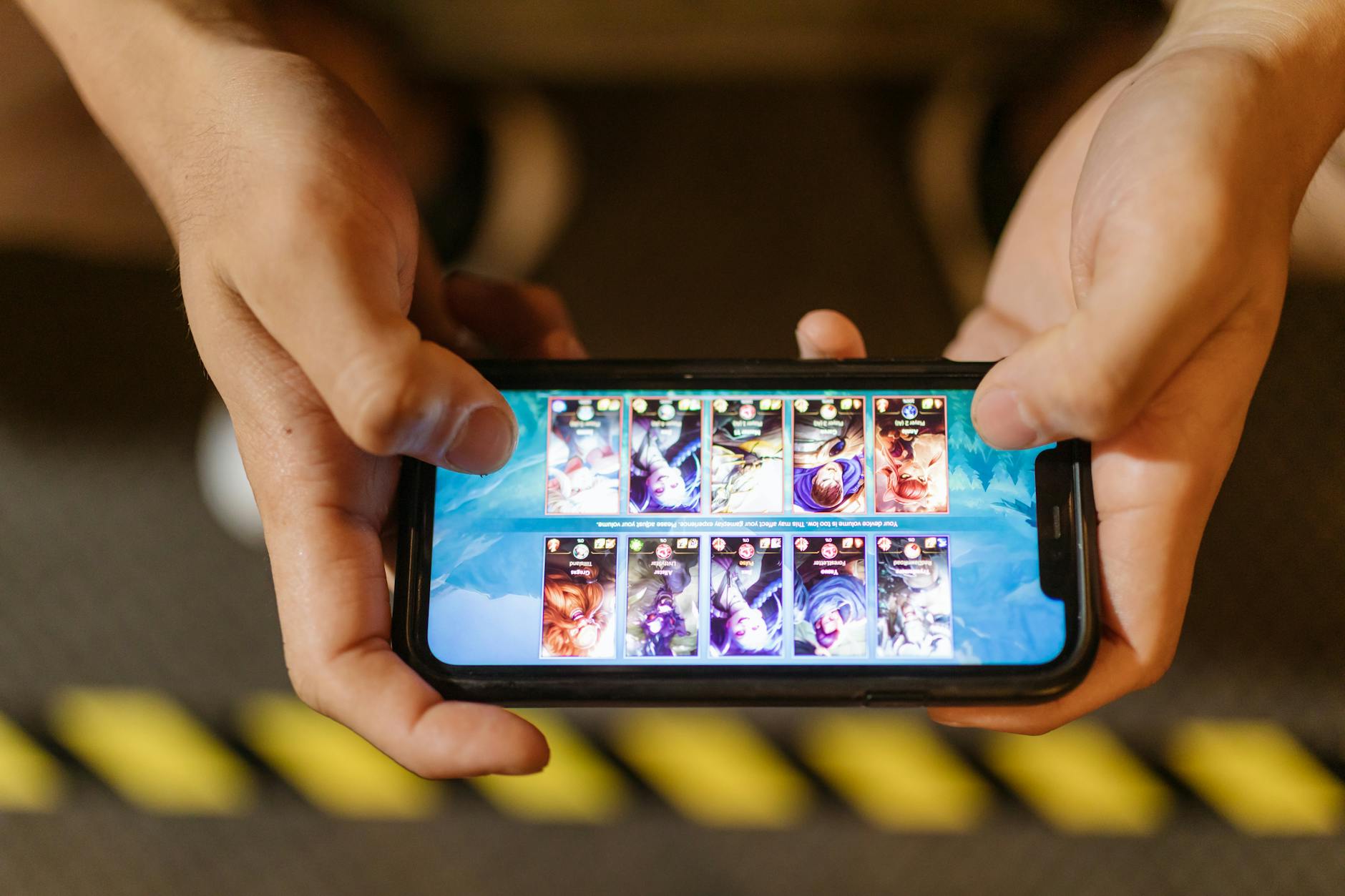 Person playing mobile game on smartphone with colorful game interface visible on screen