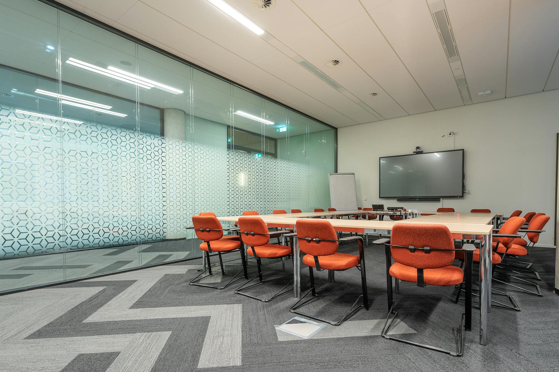 Modern corporate meeting room with presentation screen showing business metrics