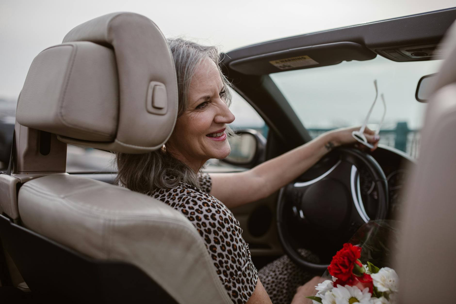 Senior woman driving car, representing rural residents who must travel long distances for healthcare services