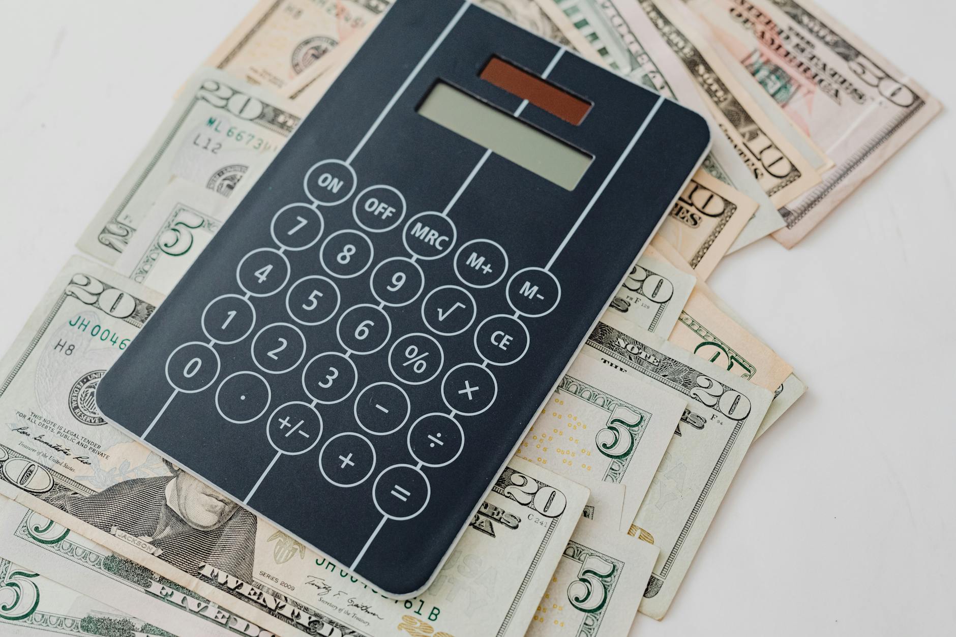 Financial calculator next to stacks of money and investment documents on desk
