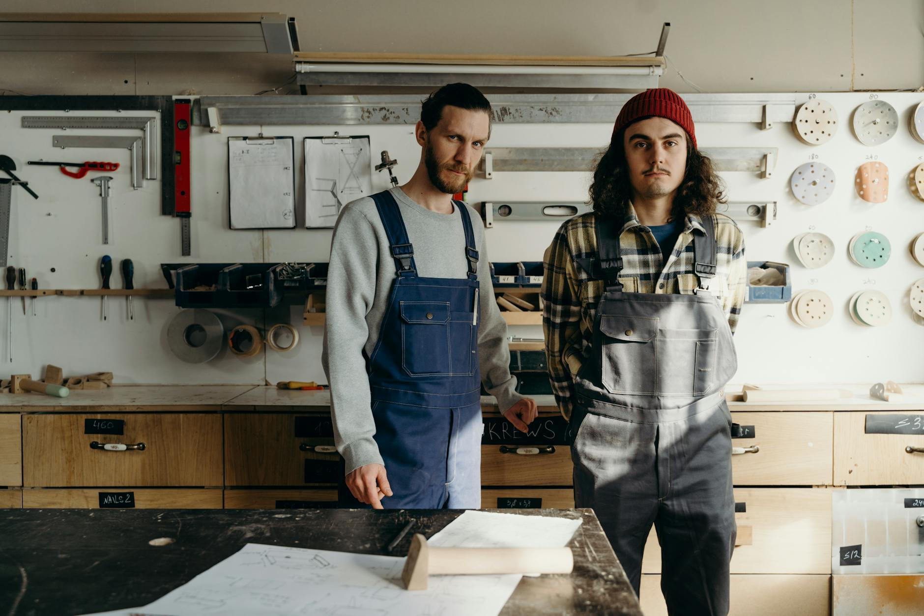 Young person learning technical skills from experienced mentor in workshop