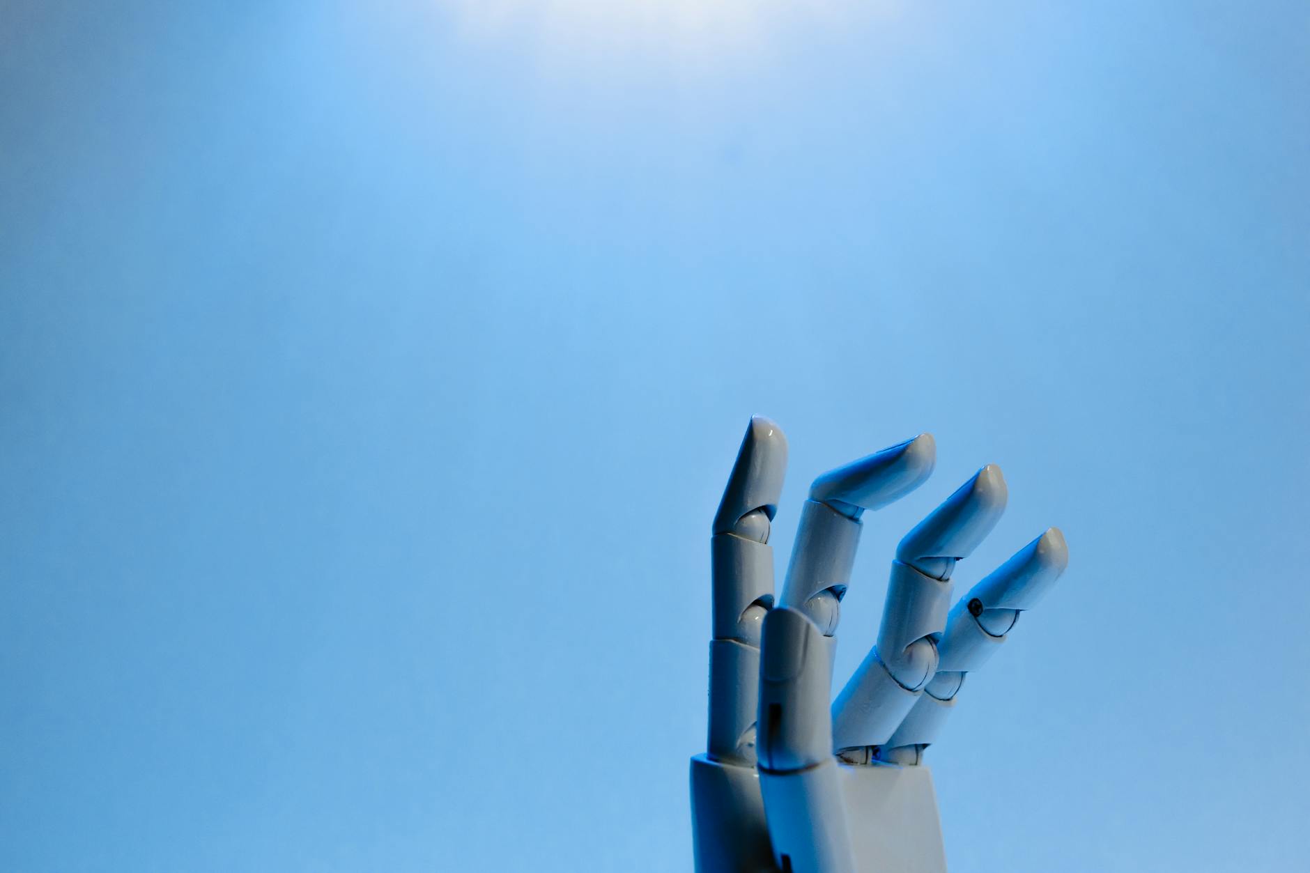 Robotic hand positioned over laptop keyboard representing AI automation