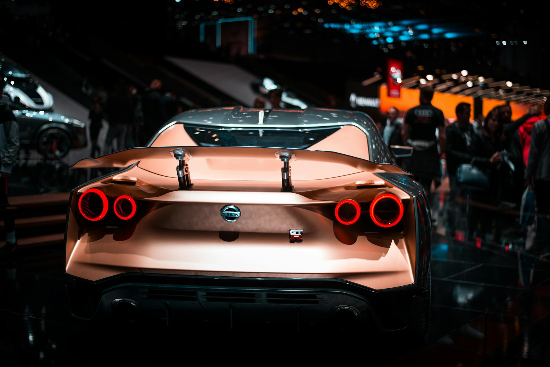 Modern vehicles displayed at an automotive exhibition with visitors examining latest models