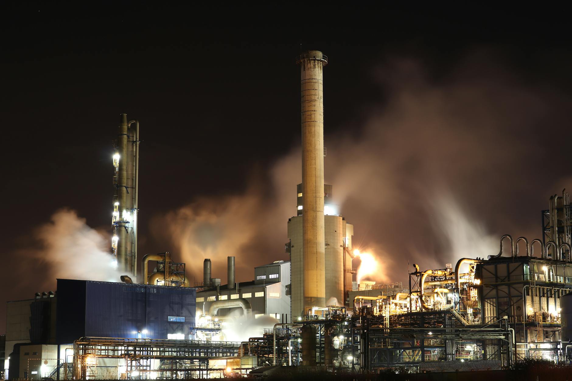 Industrial oil refinery complex with storage tanks at sunset