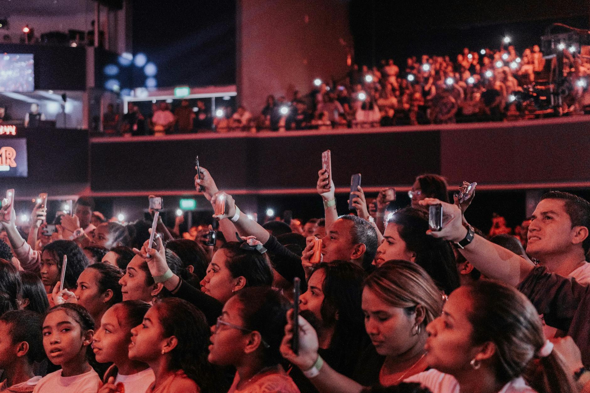 Large concert audience with hands raised at live music venue