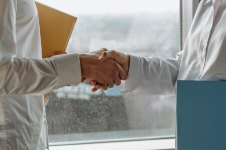 Two hands in business attire reaching across table in diplomatic gesture