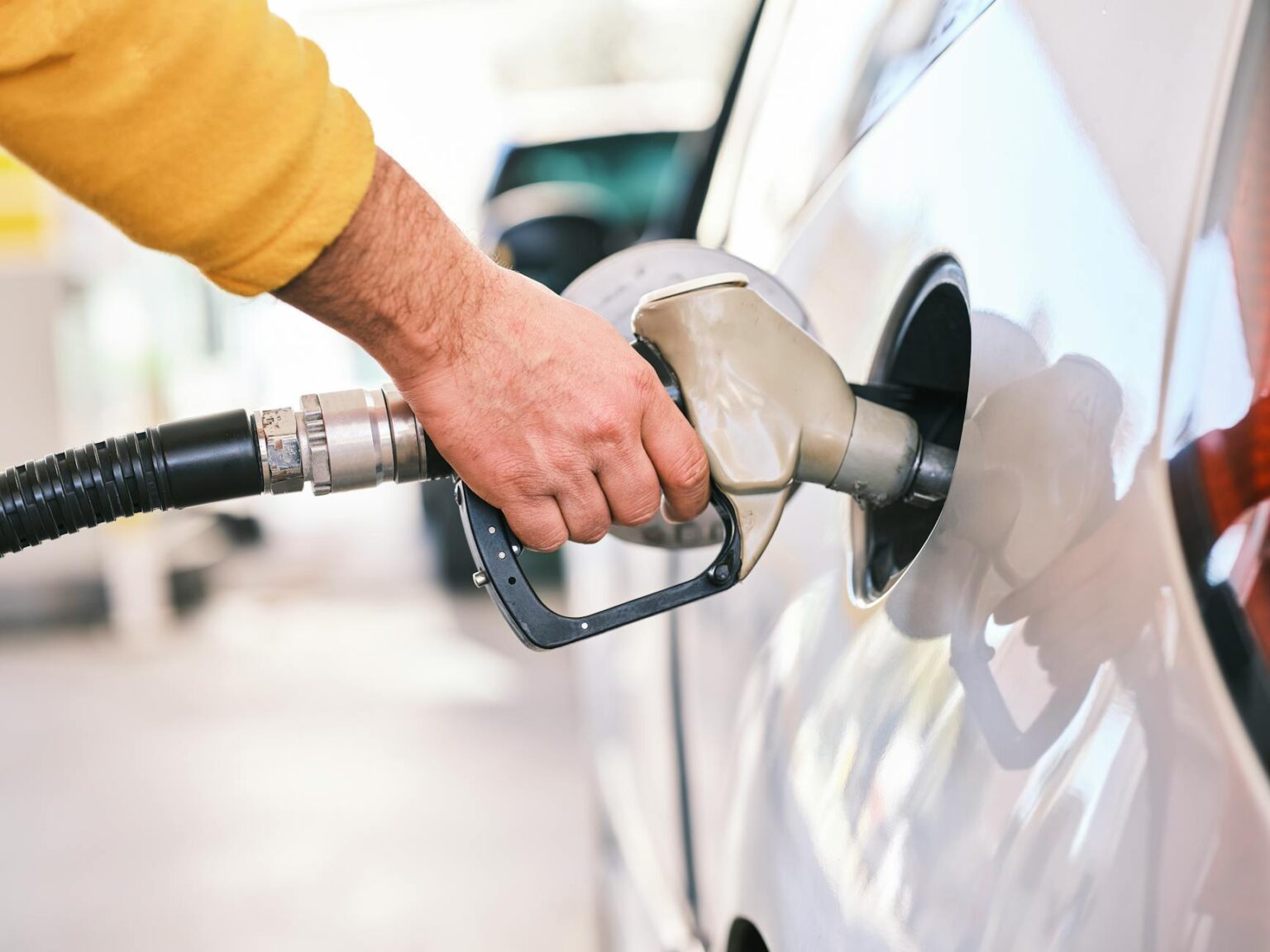 Person filling up car with gasoline at fuel station
