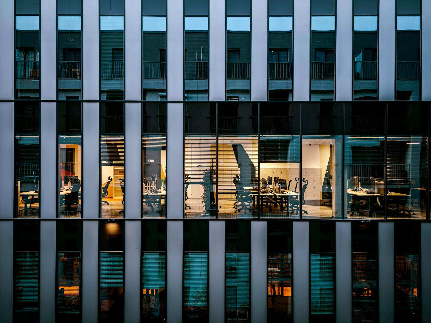 Modern corporate office building exterior with glass windows reflecting sky