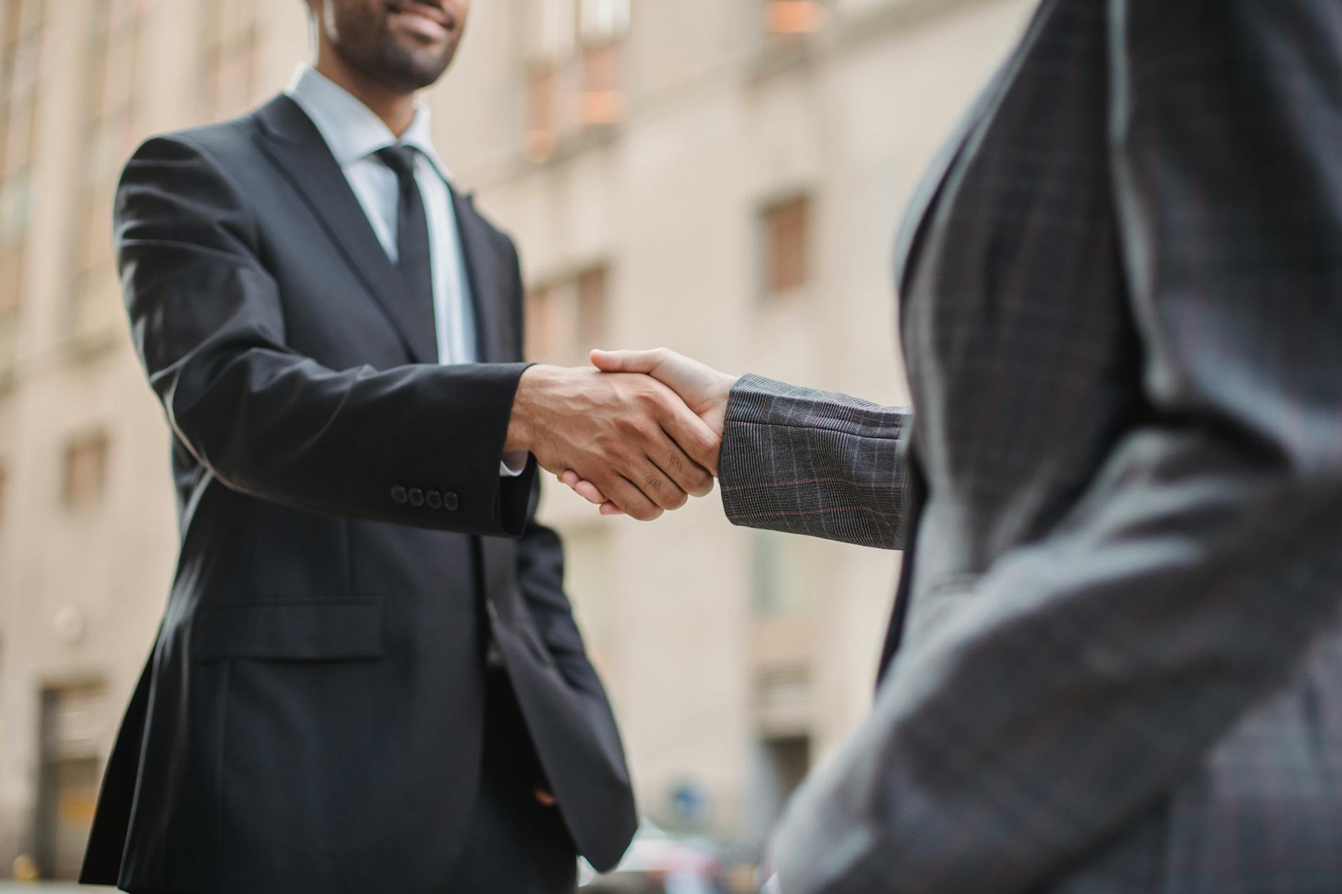 Business professionals shaking hands over signed contracts
