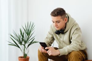 Young teenager scrolling on a smartphone in a dimly lit room