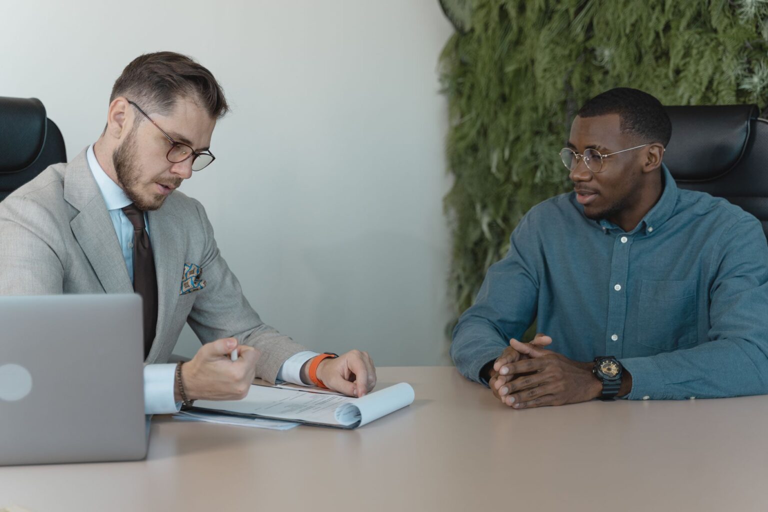 Two people shaking hands across a desk during a job interview