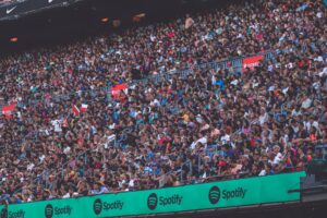 Fans gathered outside a large sports stadium holding tickets and phones