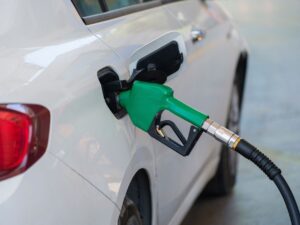 Driver filling up at a gas station pump showing price per gallon