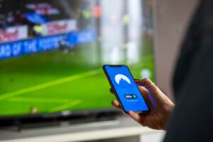 Person holding a remote control in front of a streaming television screen