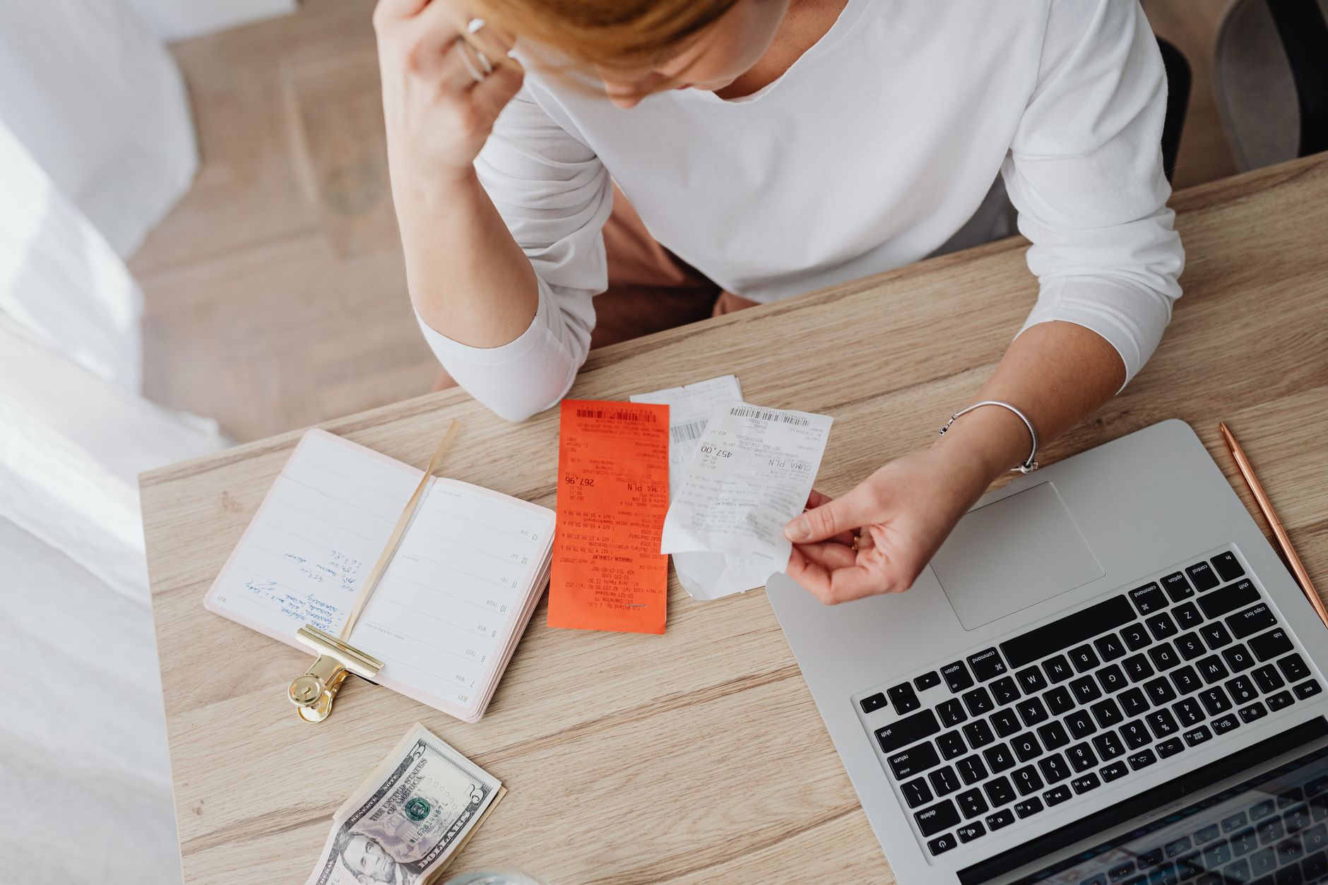 Person reviewing bills and budget documents at kitchen table