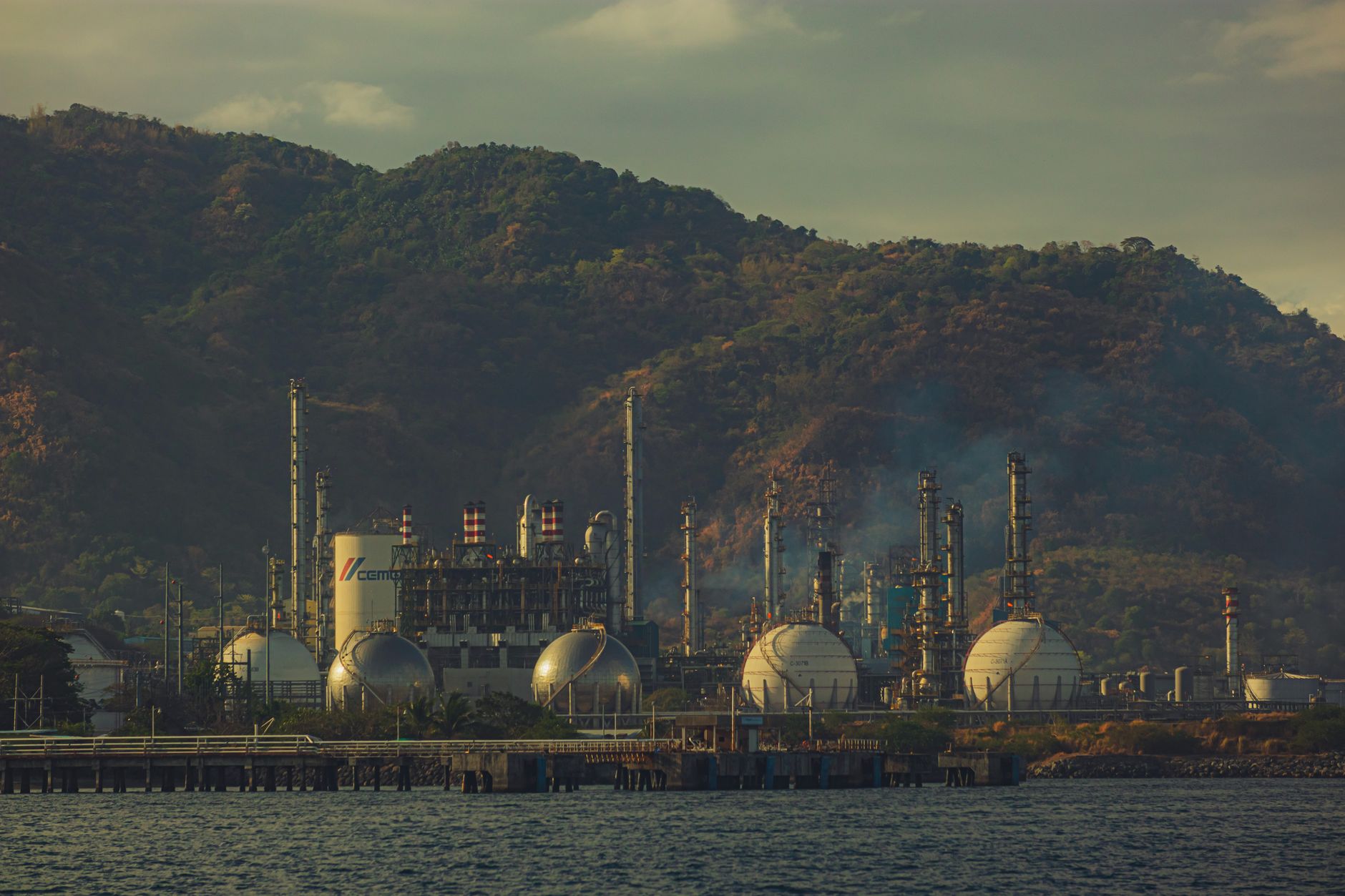 Oil refinery with pipes and storage tanks at dusk