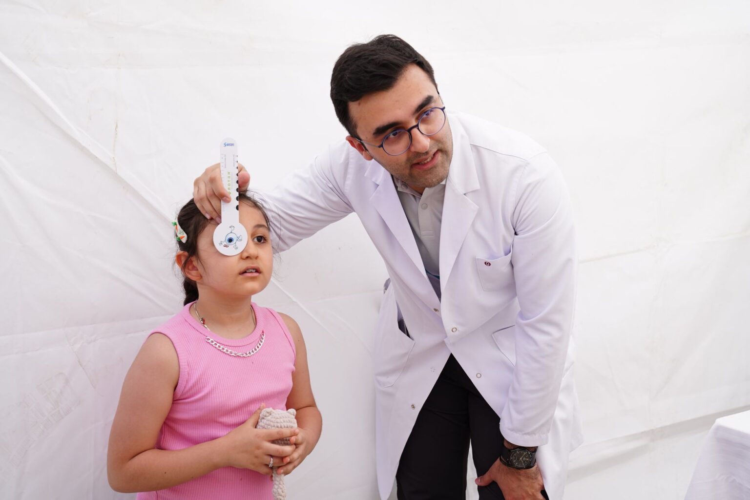 A pediatrician examining a young child during a routine well-child visit