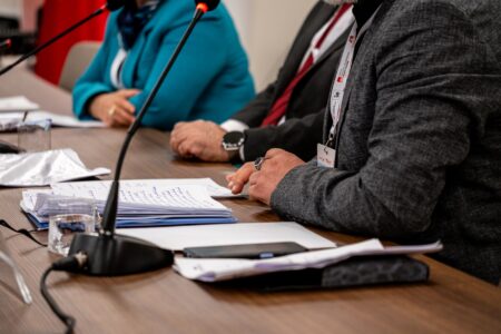 Two officials seated across a formal diplomatic negotiating table