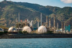 Large oil refinery with smokestacks and storage tanks at dusk