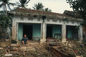 Storm-damaged home with roof destruction representing rising insurance costs