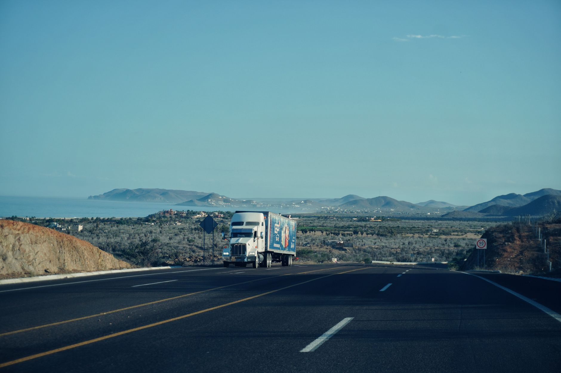 A large diesel freight truck driving on an American highway at dusk